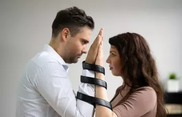 Mâinile cuplului legate unul de celălalt înfățișând a fi codependenți într-o relație